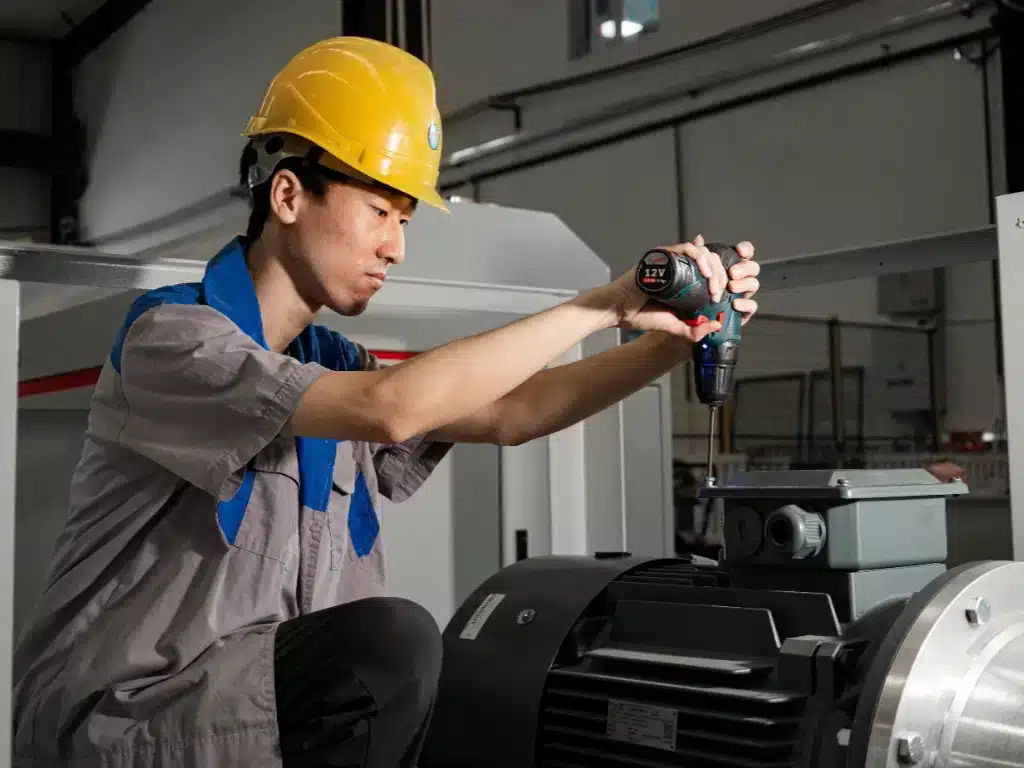 A close-up of a technician in a hard hat using a drill on a 设备.
